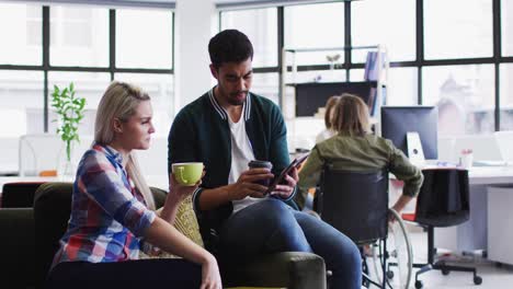 Diversos-Colegas-De-Oficina,-Hombres-Y-Mujeres,-Discutiendo-Sobre-Una-Tableta-Digital-Mientras-Toman-Café-En-Modo