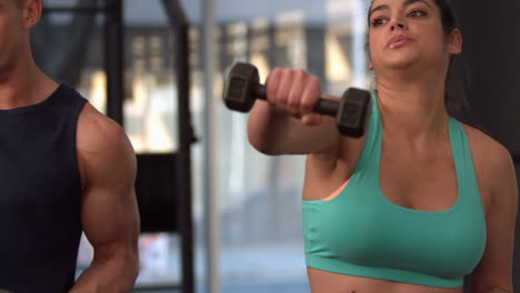 Smiling-muscular-couple-lifting-dumbbells