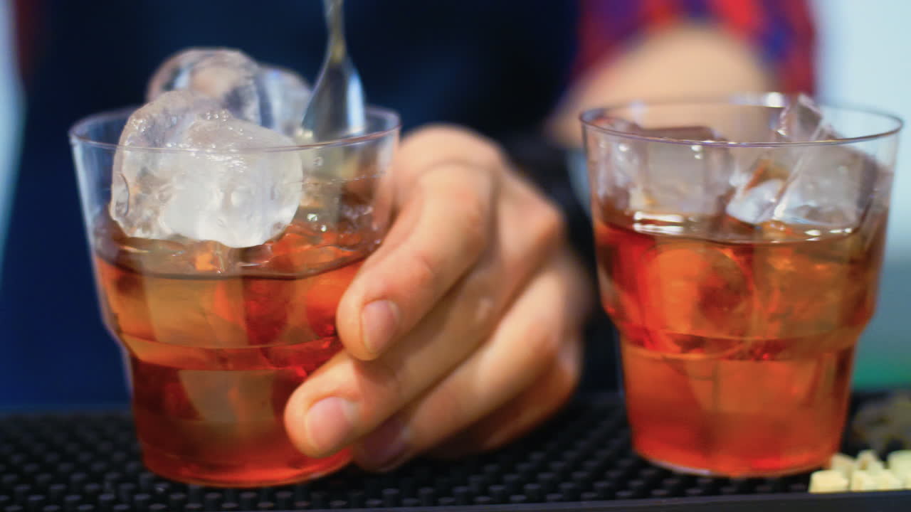 Barman preparing cocktail at bar. Bartender stirring alcoholic drink with ice