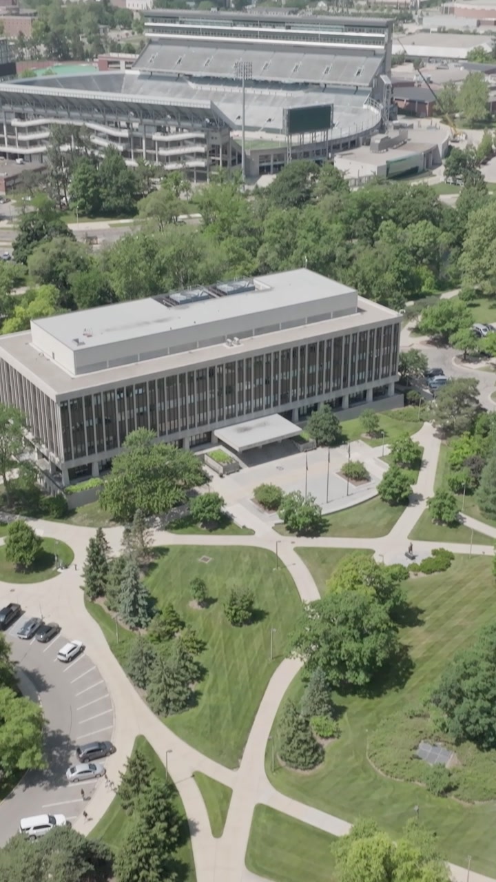 Vertical reel aerial drone video tilting upward on the Hannah Community Center at Michigan State University, capturing a recognizable campus building from above in a cinematic view.