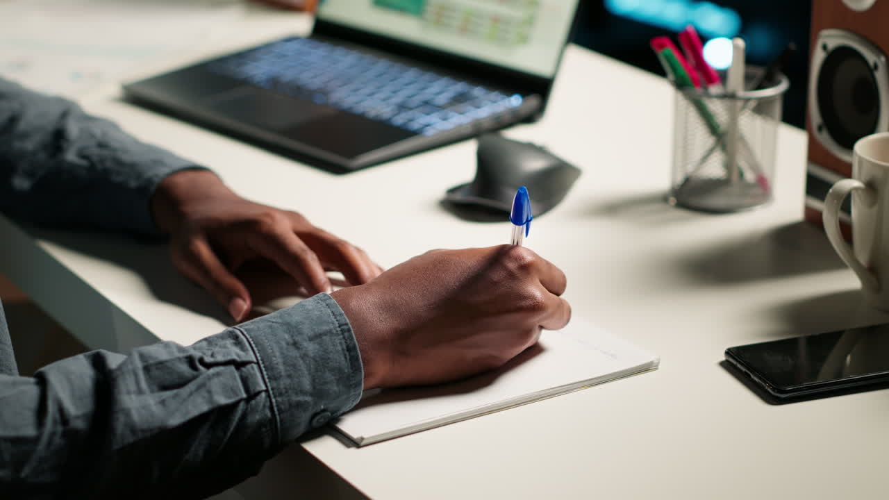 Afro-Amerikaanse persoon die op afstand werkt en projectnotities opstelt
