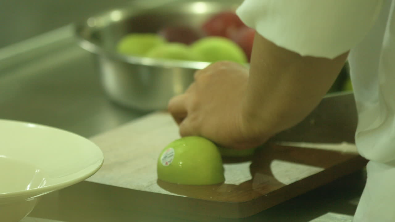 도마 위에서 녹색 사과를 자르는 요리사
