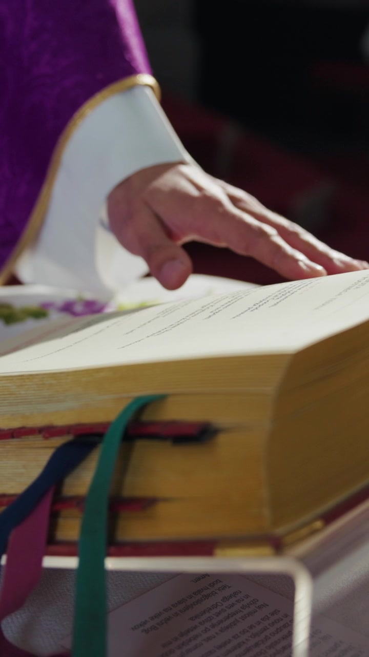 Sacerdote in una veste viola, una casula, che sfoglia le pagine di un messale, un libro liturgico del