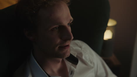 man sitting in armchair at night