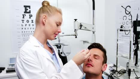 female optometrist putting eye drop in patient eyes