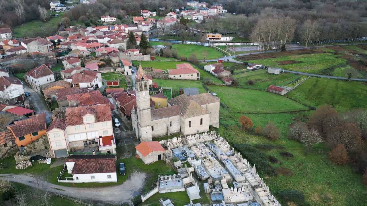 drones orbitan la alta torre del campanario de ladrillo de la iglesia y el cementerio con vistas a los campos de hierba en la ciudad española