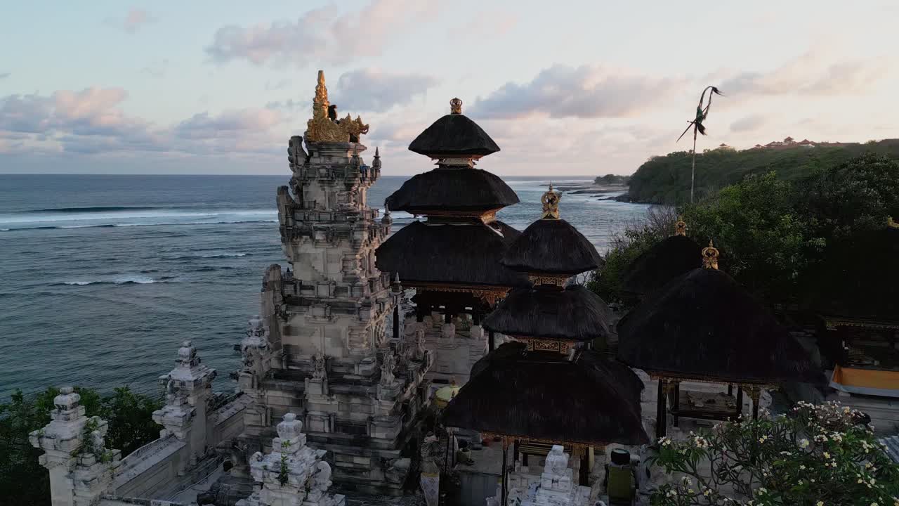 Aerial view of a traditional Balinese seaside temple surrounded by lush greenery and ocean breeze, capturing the sacred beauty of Indonesia’s coastal heritage under soft golden light