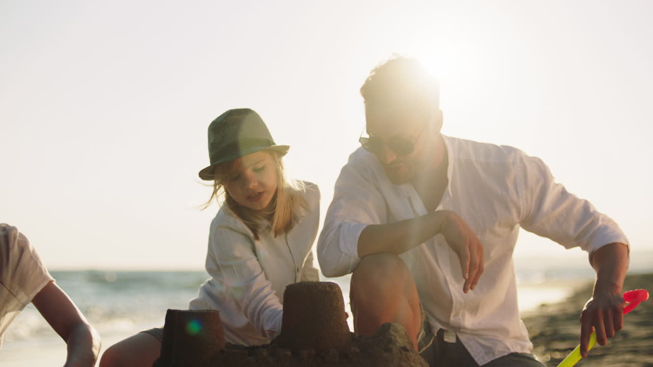 일몰 때 해변에 모래 성을 짓는 가족