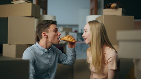 una pareja comiendo en un nuevo apartamento entre cajas de cartón. la familia disfruta de su nuevo hogar.