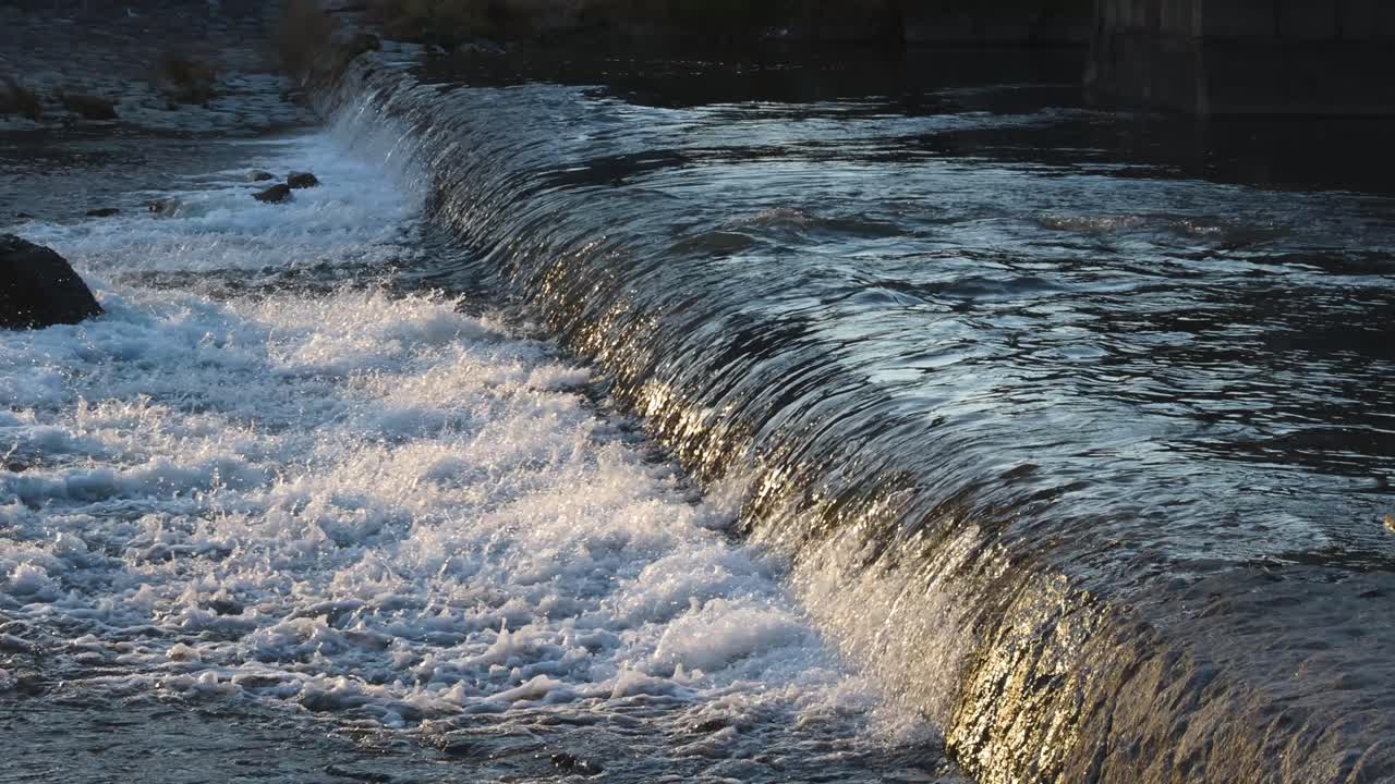 Sunlit waterfall flowing over rocky cascade