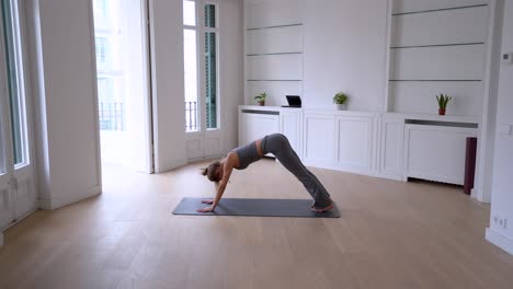 flexible female practicing yoga on mat in room