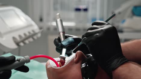 face of a patient in protective glasses at dentist's visit. stomatologist together with a nurse working with dental tools during teeth treatment. close-up.