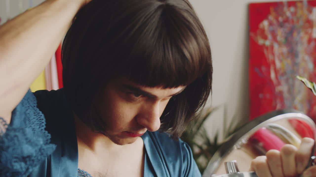 hombre transgénero cepillando el cabello de la peluca en casa