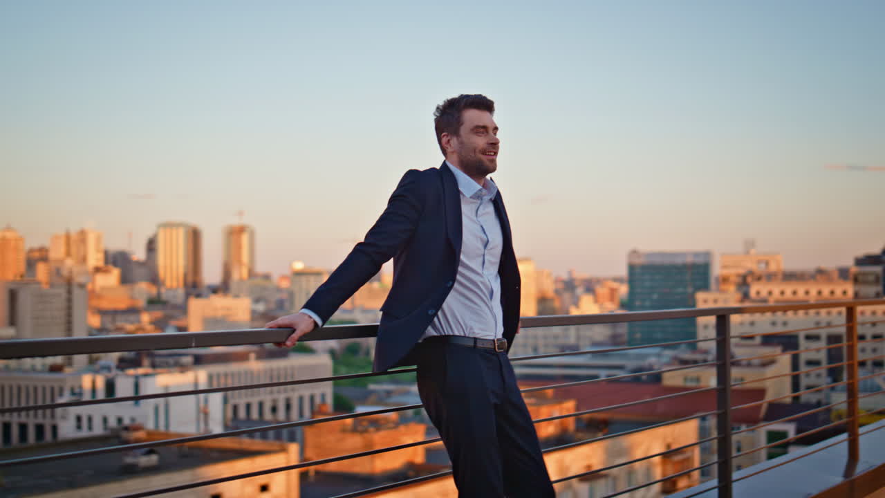 Smiling ceo relaxing outdoors terrace contemplating sunset cityscape. Happy man