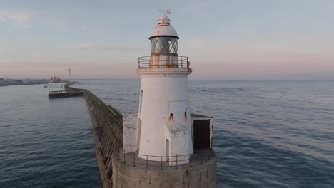 drone clip showing long jetty harbour wall and traditional lighthouse with glass windows