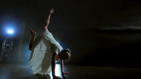 a woman in a white dress is dancing on the stage the dramatic dances of modern ballet. a ballet dancer moves plastic performing modern choreography in smoke.