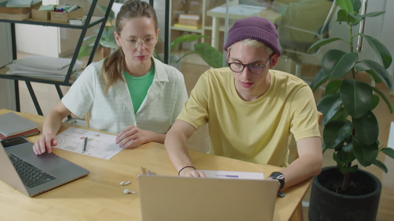Gen Z Coworkers Using Laptops and Speaking in Office