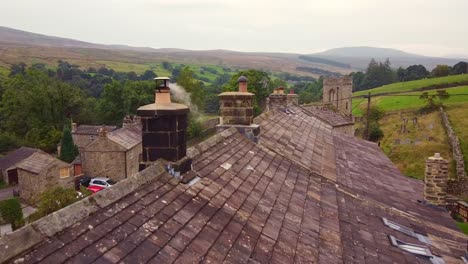 drone aerial shot of old stone cottage chimney and smoke over yorkshire village