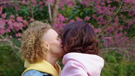 lesbian couple kissing under cherry blossoms
