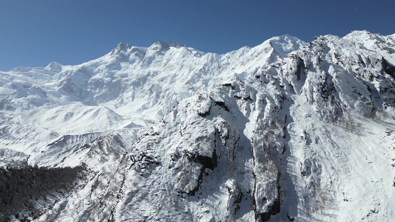 Breathtaking high-altitude drone panorama showcasing the sheer scale and massive rocky ridges of the snow-capped Himalayan mountain range towering above Fairy Meadows Pakistan