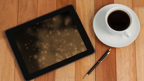 Animation-of-tablet-with-light-trails-on-screen-and-cup-of-coffee-on-desk