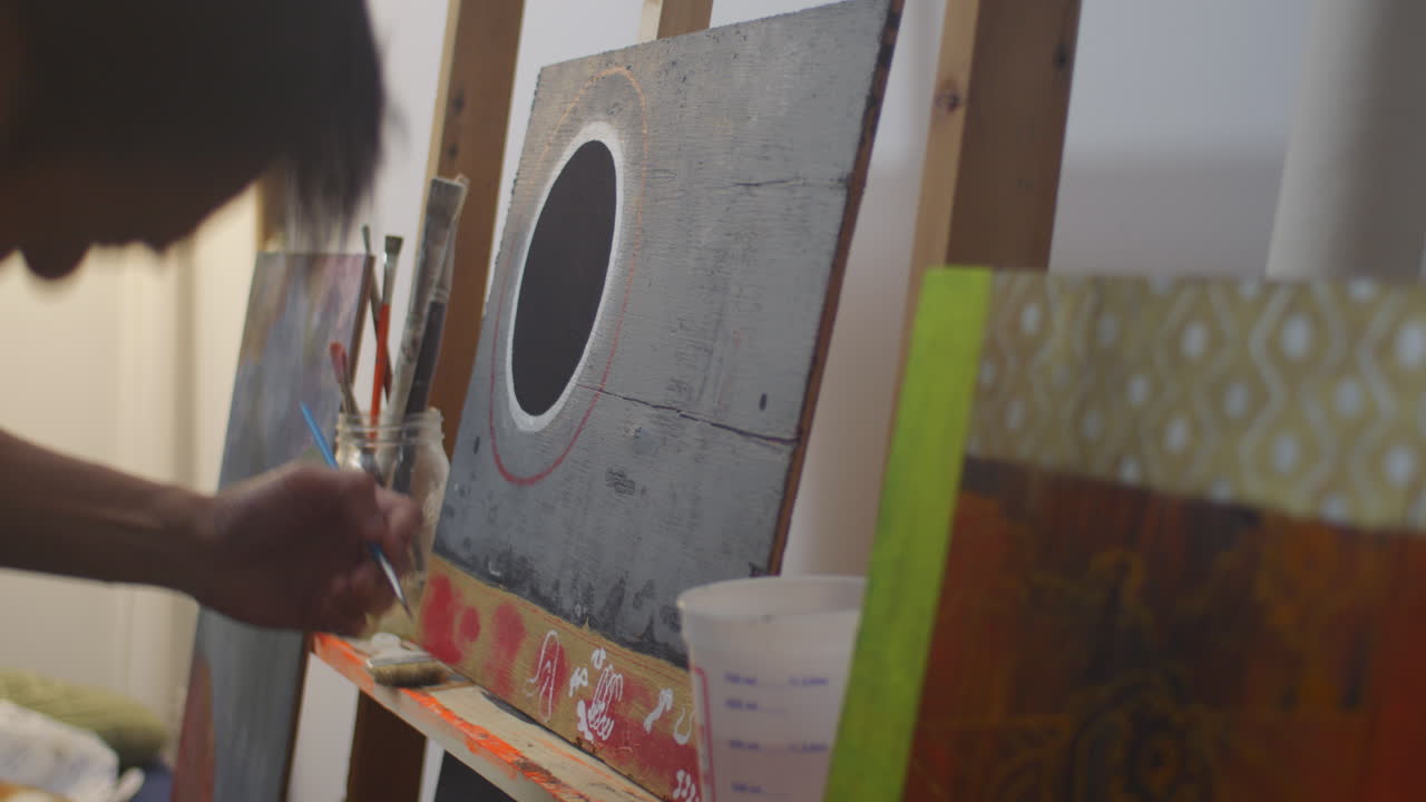 artista en el trabajo, aplicando colores de su paleta y en la pintura