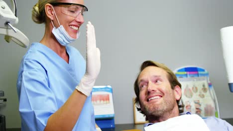 Female-dentist-giving-high-five-to-male-patient