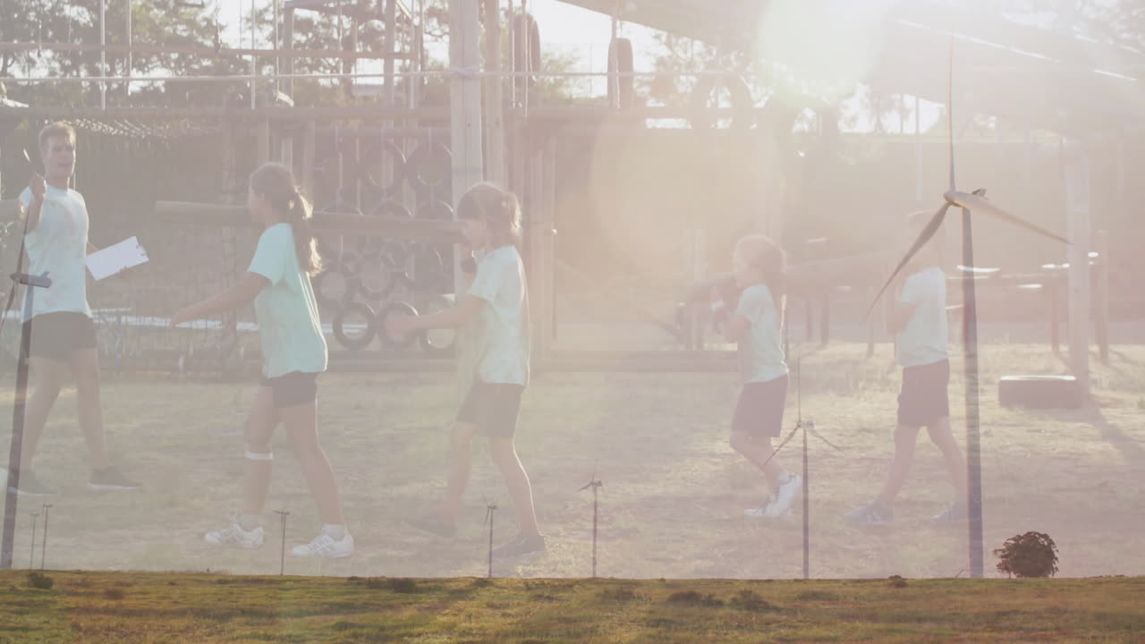 Playing at playground, children with animation of wind turbines in sunny landscape