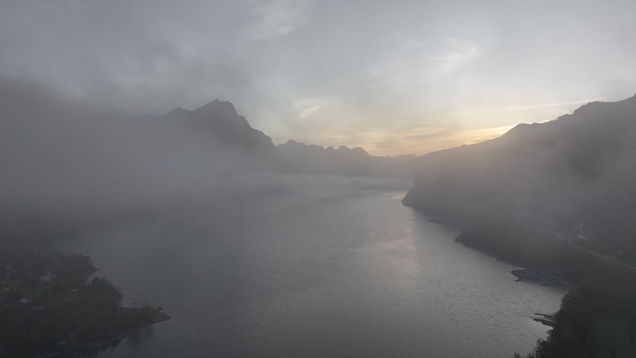 스위스의 산의 희미한 실루과 함께 해가 뜨는 동안 안개로 가득 찬 렌세 호수