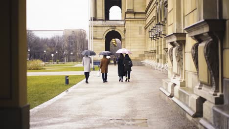 Gruppe-Von-Menschen,-Die-Im-Regen-Mit-Regenschirm-In-Der-Münchener-Innenstadt-In-Der-Nähe-Eines-Parks-Spazieren-Gehen
