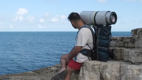 backapcker boy watching sea