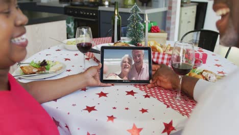 Pareja-Afroamericana-Sonriente-Usando-Tableta-Para-Videollamada-Navideña-Con-Pareja-Feliz-En-Pantalla