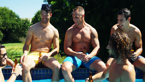 grupo de amigos sentados en el lado de la piscina y disfrutando de bebidas