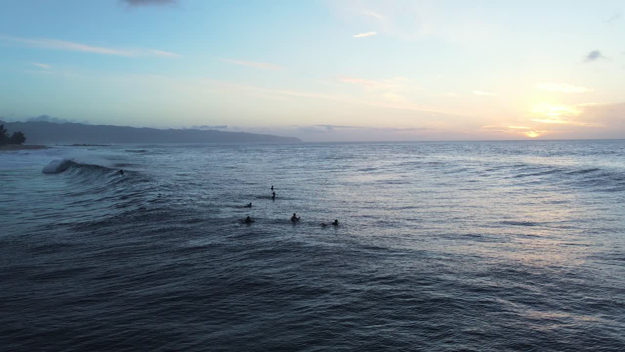 Surfisti in attesa di una grande onda del mare al tramonto, costa nord dell'isola di Oahu, Hawaii.
