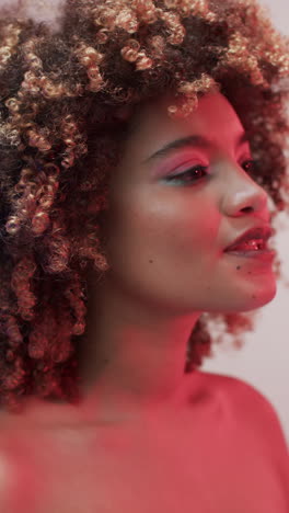 vertical video of biracial woman with dark hair in pink light, slow motion