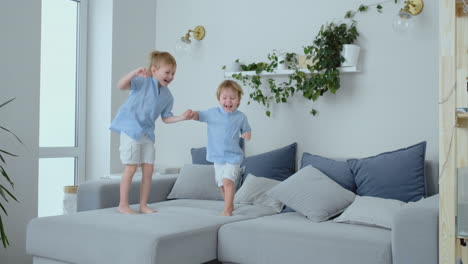 two little boys jumping on the couch and having fun. joy, laughter and fun at home