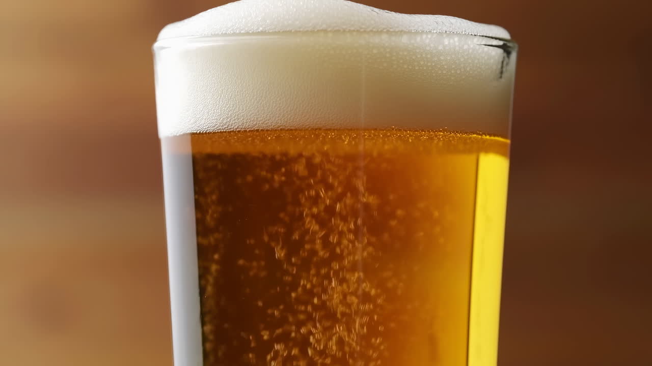Primo piano di schiuma di birra che mostra una lager ambrata dorata, schiuma cremosa, flusso costante di bollicine che salgono