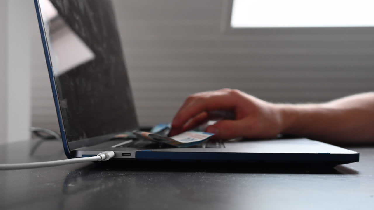 un usuario de una computadora portátil está escribiendo en su computadora mientras que los billetes de banco de 100 dólares caen en el teclado