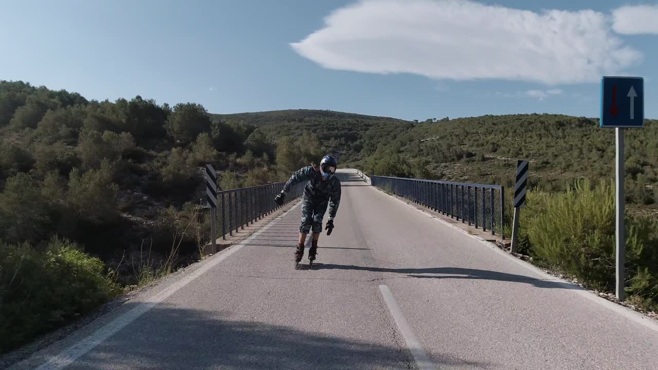 Front facing follow shot of roller skater speeding up on a mountain road