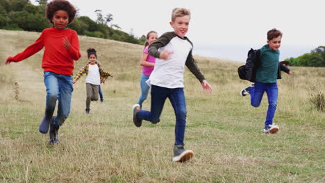 front view of group of children on outdoor activity camping trip running down hill