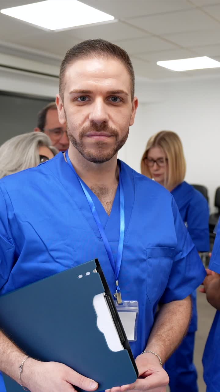 Profesional médico masculino serio con uniforme quirúrgico azul sosteniendo una carpeta.
