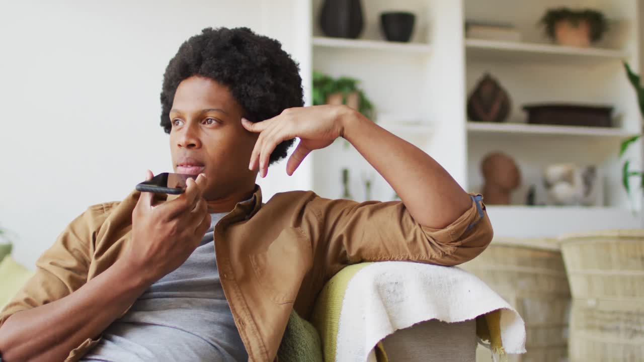 아프리카계 미국인 남자가 집에서 스마트폰을 사용합니다.