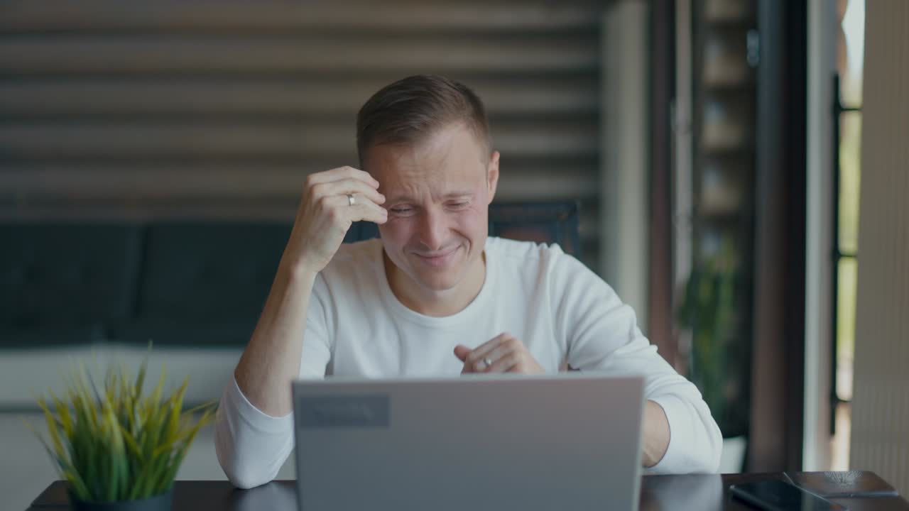 joven molesto cubriendo la cara con la palma de la mano en desesperación después de leer malas noticias en la computadora portátil