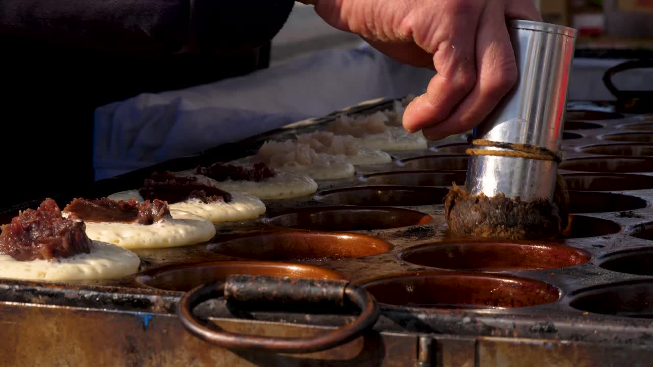 el hombre engrasa la plancha para panqueques japoneses en un festival tradicional
