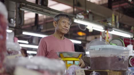 elderly market vendor weighing goods