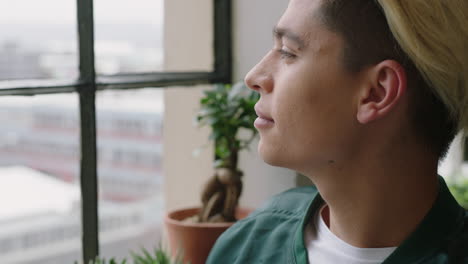 stylish young hispanic man student drinking coffee at home looking out window thinking planning ahead smiling enjoying relaxing lifestyle wearing trendy fashion hairstyle