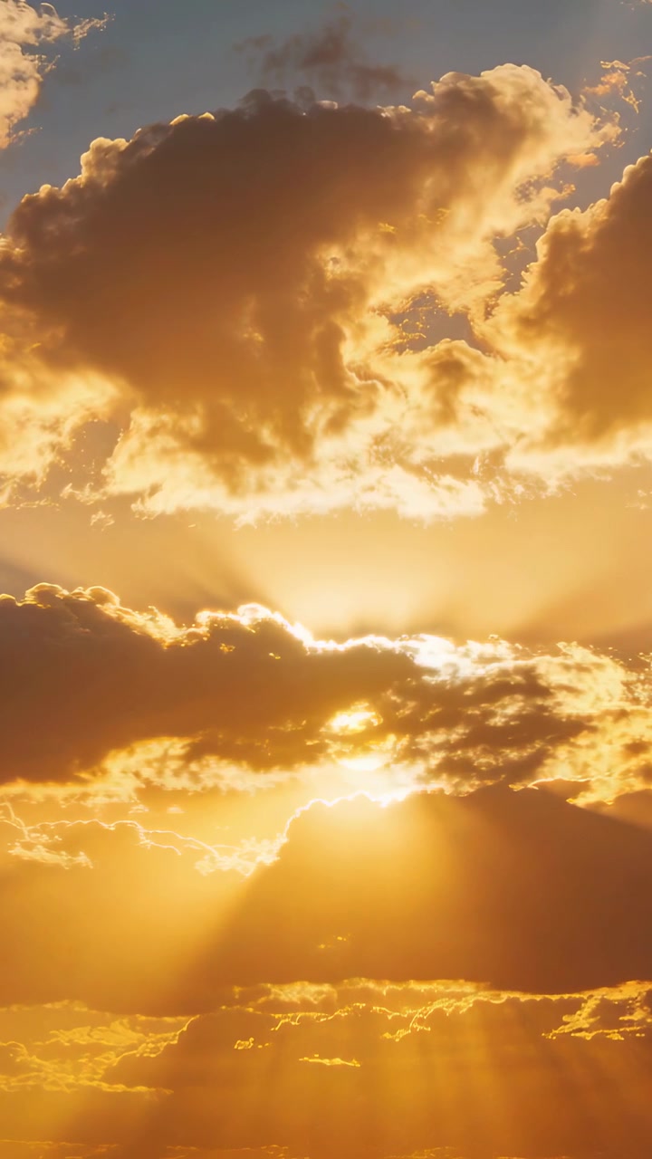 Vertical video: Shifting clouds uncovering sun, casting flickering rays over low hill at sunrise