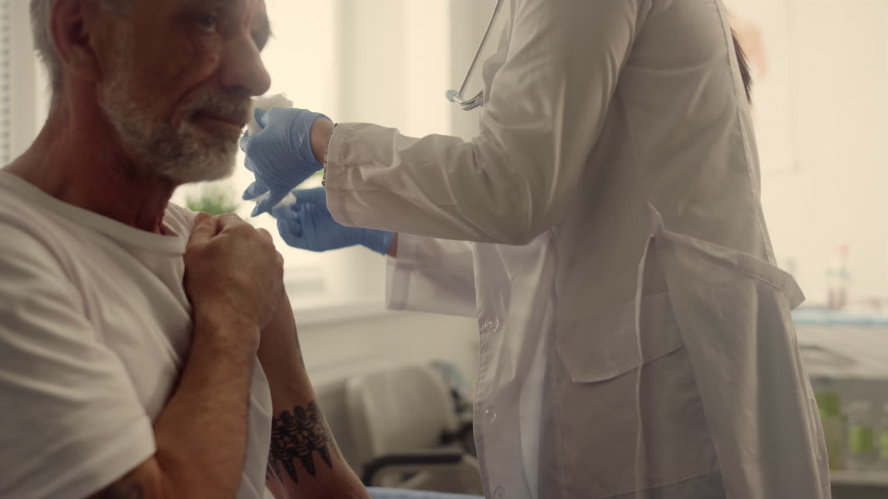 Doctor hands injecting covid vaccine old man close up. Physician sterilize arm.