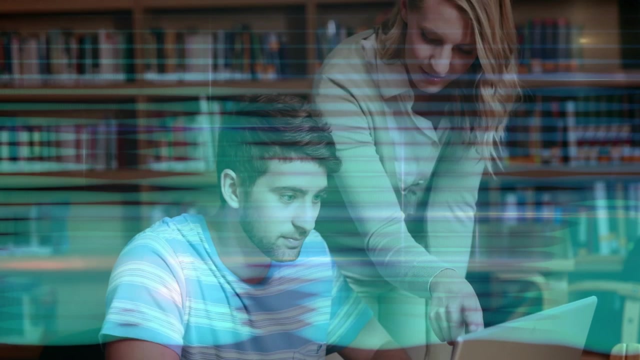 Student pausing typing on laptop in university library while peer pointing screen guiding edits