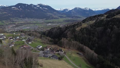 drone rise up and reveals amazing view over cityscape surrounded by snow covered summits in amerluegen, vorarlberg, austria